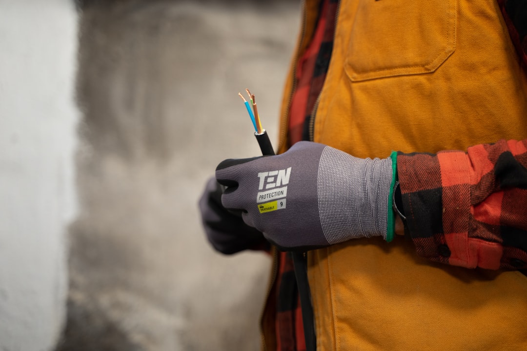 core-values An electrician with work gloves holding a wire.