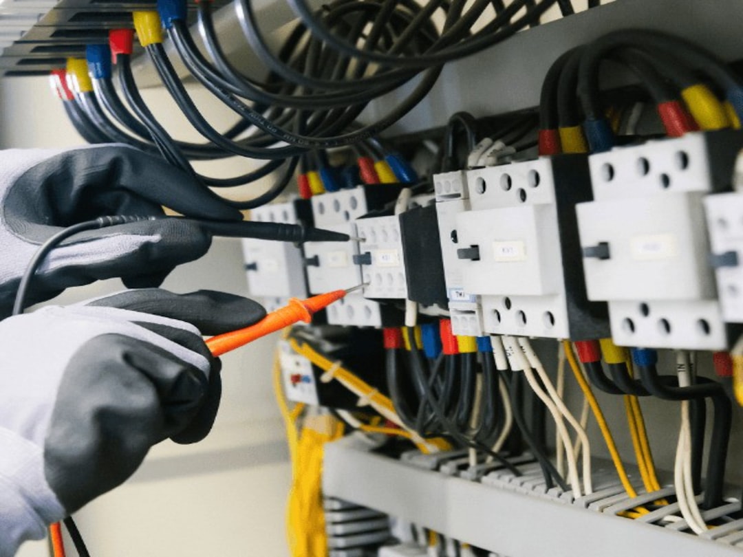 creative-approach-img Electrician testing electrical equipment and wiring inside a control panel.